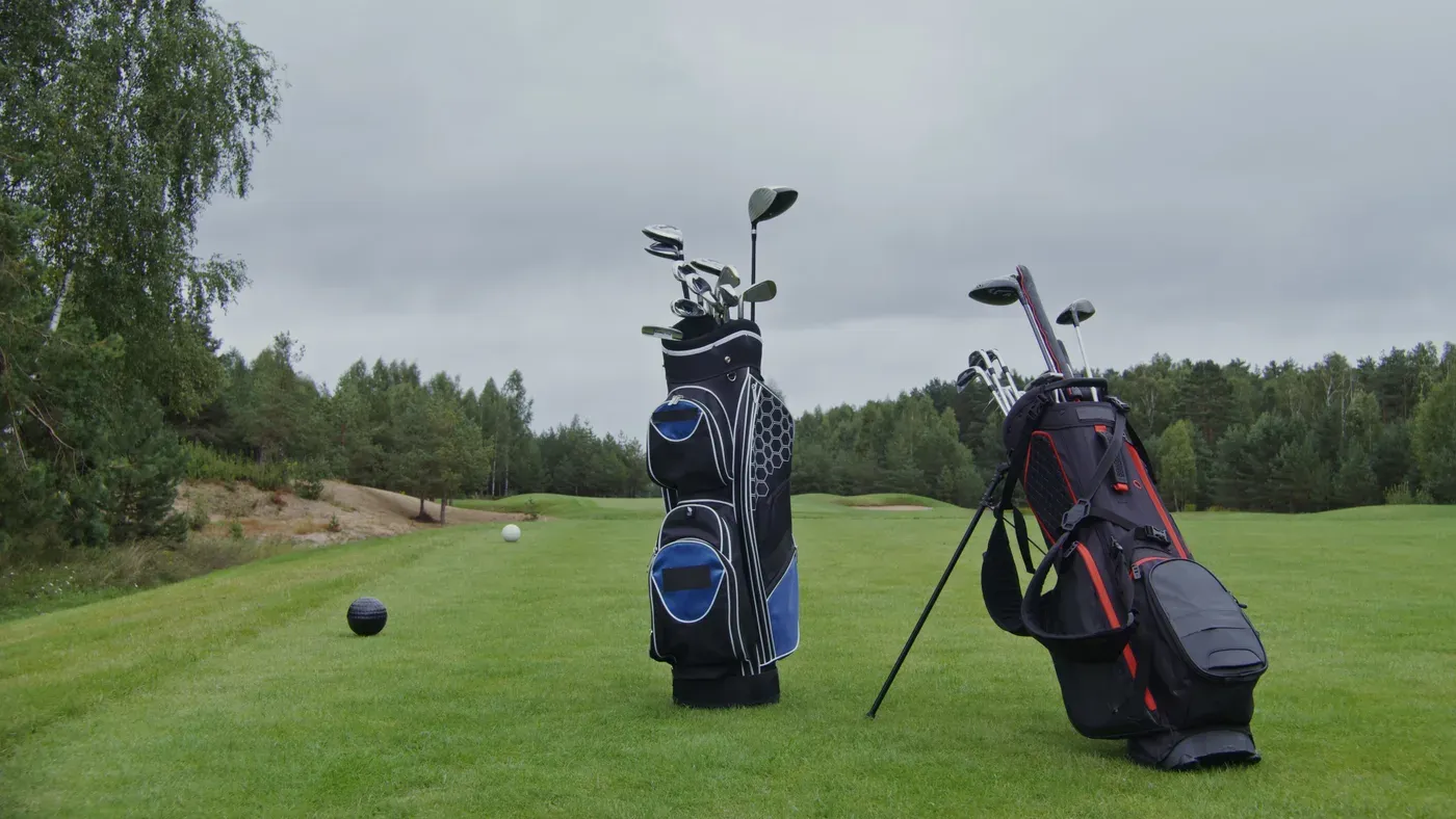 Svart golfbag med klubbor bredvid två golfspelare