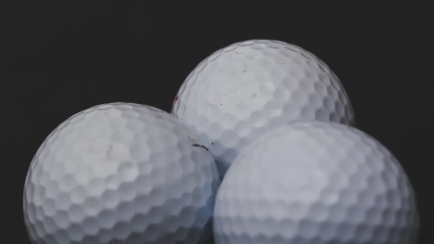 Tre golfbollar i närbild mot mörk bakgrund