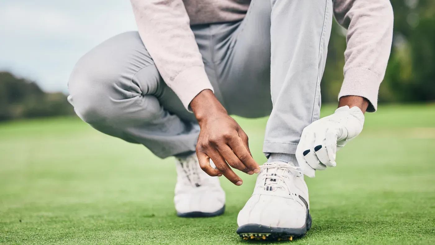 Golfare snörar sina bästa golfskor ute på banan