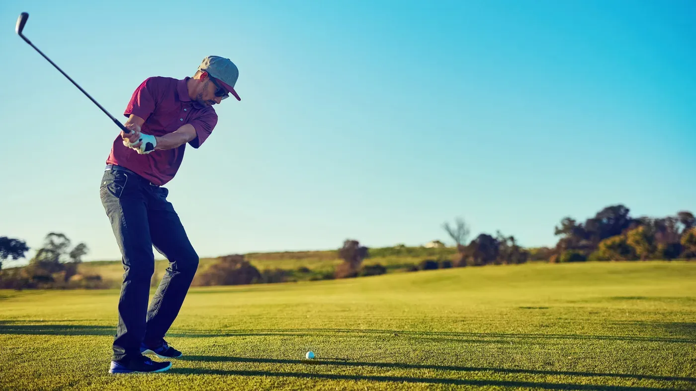 Golfare svingar bästa fairwayträ ner mot bollen